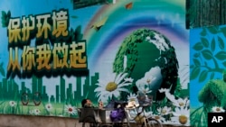 一名工人在北京的一面"保護環境從你我做起"的宣傳畫前休息。（2017年6月5日）