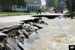Un transeúnte camina cerca de una calle dañada por las aguas de la inundación, el martes 11 de julio de 2023, en Ludlow, Vermont, EEUU. (Foto AP/Steven Senne)