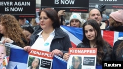 Women hold images of hostages held in Gaza, during a march against antisemitism, in London, Nov. 26, 2023. 