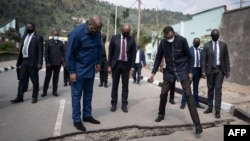 Le président rwandais Paul Kagame (C-D) et le président de la RDC Félix Tshisekedi (C-G) regardent une fissure après une éruption volcanique sur la route de Rubavu, au Rwanda, le 25 juillet.