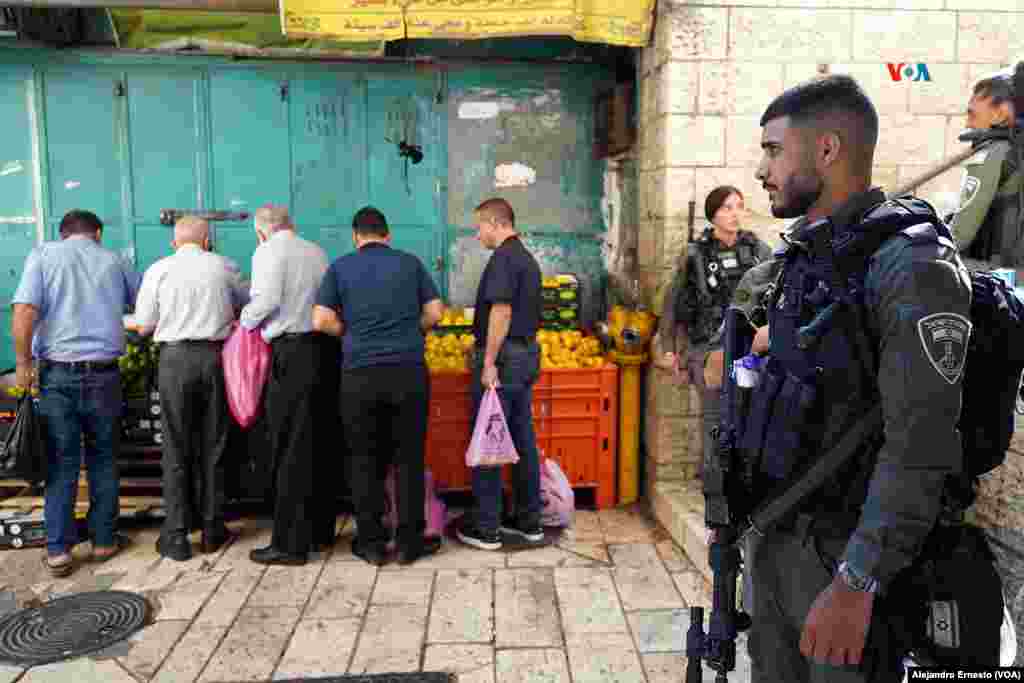 Varios palestinos hacen sus compras, bajo la mirada de un policía de fronteras de Israel, en la Puerta de Herodes, uno de los accesos al barrio árabe de la Ciudad Vieja de Jerusalén.