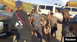 Orang-orang membawa jenazah di samping kendaraan yang diparkir di pinggir jalan setelah penyergapan di Provinsi Enga, Papua Nugini, 19 Februari 2024. ( Foto: melalui Reuters)