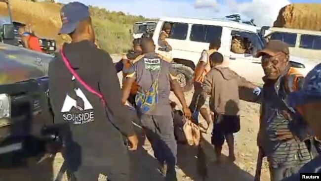 People carry a body after an ambush in Enga Province, Papua New Guinea, according to the Australian state broadcaster in this screen grab obtained from a social media video released on Feb. 19, 2024.