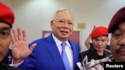 FILE: Mantan Perdana Menteri Malaysia Najib Razak dikawal oleh petugas penjara, melambaikan tangannya ke arah fotografer saat meninggalkan pengadilan seusai sidang di pengadilan Kuala Lumpur, Malaysia, 19 Januari 2024. (REUTERS/Hasnoor Hussain)