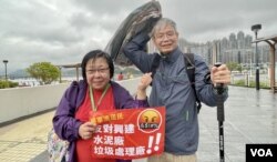 将军澳反填海游行纠察赵小姐，与手持报纸挡雨、年约70岁的将军澳居民林和平 (美国之音/汤惠芸)