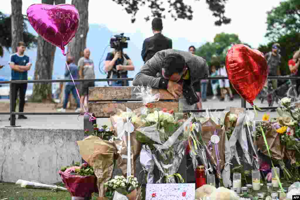 A man reacts in front of flowers and candles for victims of a stabbing attack that happened the day before in the Jardins de l&#39;Europe park in Annecy, French Alps. A man armed with a knife stabbed four preschool children and two adults.