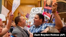 Pastor Michael Shover of Christ the Redeemer Church in Pella, left, argues with Ryan Maher, of Des Moines, as protestors clash in the Iowa State Capitol rotunda, July 11, 2023. (Zach Boyden-Holmes/The Des Moines Register via AP)