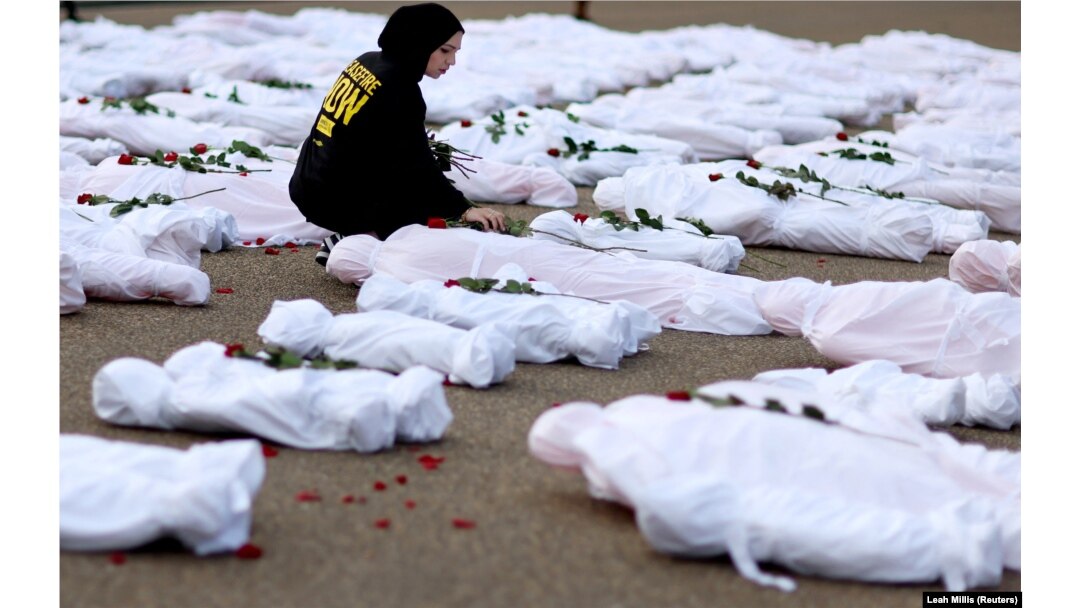 Isra Chaker dari Amnesty International AS meletakkan bunga mawar bagian dari aksi protes yang menuntut Israel mengizinkan bantuan kemanusiaan tanpa hambatan ke Gaza di depan Gedung Putih di Washington, AS, 15 November 2023. (Foto: REUTERS/Leah Millis)