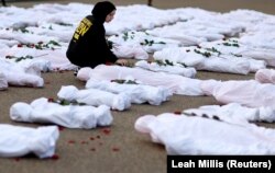 Isra Chaker dari Amnesty International AS meletakkan bunga mawar bagian dari aksi protes yang menuntut Israel mengizinkan bantuan kemanusiaan tanpa hambatan ke Gaza di depan Gedung Putih di Washington, AS, 15 November 2023. (Foto: REUTERS/Leah Millis)