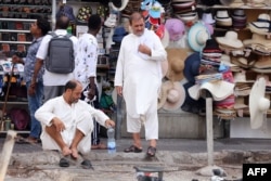 Workers rest along a pavement on a hot summer day in Dubai on July 12, 2023.