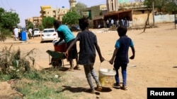 FILE - Children carry a bucket of water during clashes between the paramilitary Rapid Support Forces and the army in Khartoum North, Sudan, April 22, 2023.