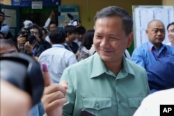 Hun Manet, center, of the Cambodian People's Party (CPP), son of Cambodia Prime Minister Hun Sen, also army chief, shows off his inked finger outside a polling station after voting in Phnom Penh, Cambodia, July 23, 2023.