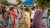 People cover their heads to shield from the heat as they buy water bottles in New Delhi, India, Tuesday, June 18, 2024.