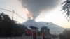 Pengendara berkendara saat Gunung Lewotobi Laki-Laki mengeluarkan asap panas di Flores Timur, Nusa Tenggara, Timur, 2 Januari 2024. (Foto: AFP/ARNOLD WELIANTO)