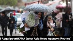 Iranian women walk through rain in a flower market, ahead of Nowruz, the Iranian New Year, in Tehran, March 16, 2023. 