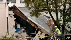 A man views damage to a building caused by recent flooding, Sept. 13, 2023, at the Hilton & Cook Marketplace in Leominster, Mass.