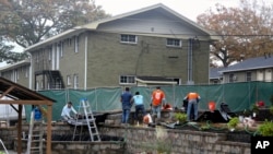In this photo provided by Gabriella Rico, volunteers from Home Depot work to build a garden and water feature on the campus of the Veterans Empowerment Organization in Atlanta, Nov. 10, 2023.