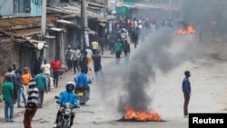 A person rides a bike past tires set on fire by protestors in Kibera slum during an anti-government protest against the imposition of tax hikes by the government in Nairobi, Kenya July 19, 2023.