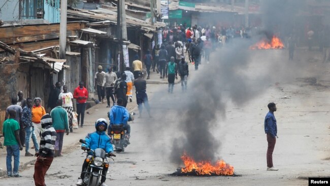 A person rides a bike past tires set on fire by protestors in Kibera slum during an anti-government protest against the imposition of tax hikes by the government in Nairobi, Kenya July 19, 2023.
