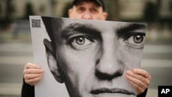 A man holds a poster with a portrait of opposition leader Alexey Navalny during a protest in front of the Russian embassy in Berlin, Feb. 16, 2024.