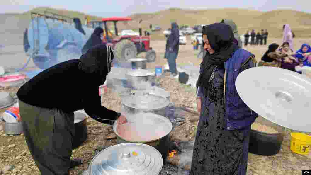 دوو ژنی گوندی باشەی گەرمیان پێکەوە خەریکی چێشت لێنانن لە سەیرانێکی گوندەکەیان