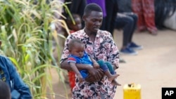 Abdikadir Omar holds one of his children at Dadaab refugee camp in northern Kenya, July 13, 2023. 