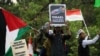 Sejumlah peserta aksi bela Palestina mengibarkan bendera Indonesia, bendera Palestina dan poster bertuliskan "Israel adalah Teroris yang Sebenarnya," di lapangan Monas, Minggu, 5 November 2023. (Foto: Indra Yoga/VOA)