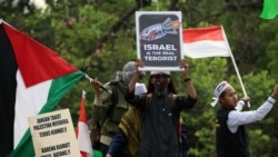 Sejumlah peserta aksi bela Palestina mengibarkan bendera Indonesia, bendera Palestina dan poster bertuliskan "Israel adalah Teroris yang Sebenarnya," di lapangan Monas, Minggu, 5 November 2023. (Foto: Indra Yoga/VOA)