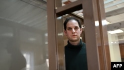 US journalist Evan Gershkovich, arrested on espionage charges, looks out from inside a defendants' cage before a hearing to consider an appeal on his extended pre-trial detention, at the Moscow City Court in Moscow, Feb. 20, 2024. 