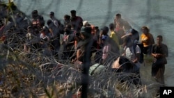 Migrants who crossed into the U.S. from Mexico are met with concertina wire along the Rio Grande, Sept. 21, 2023, in Eagle Pass, Texas.