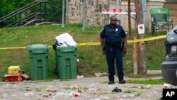A police officer stands in the area of a mass shooting incident in the Southern District of Baltimore, July 2, 2023. 