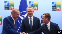 Turkey's President Recep Tayyip Erdogan, left, shakes hands with Sweden's Prime Minister Ulf Kristersson, right, as NATO Secretary-General Jens Stoltenberg looks on prior to a meeting ahead of a NATO summit in Vilnius, Lithuania, July 10, 2023. 