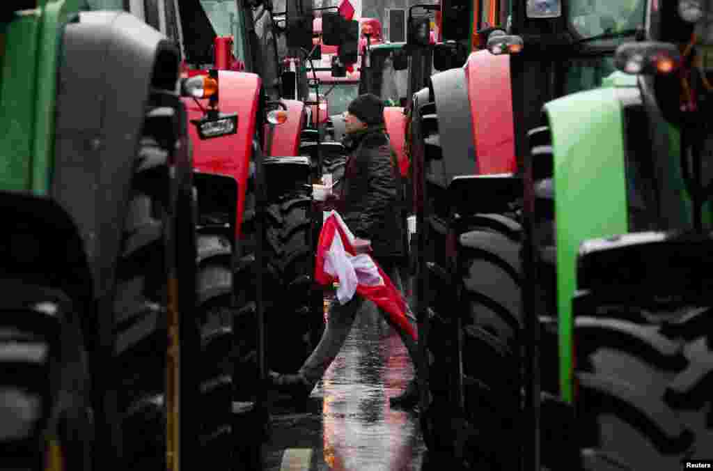 A demonstrator with a Polish flag walks among tractors on a road as Polish farmers protest over price pressures, taxes and green regulation, grievances shared by farmers across Europe, in Poznan, Poland.