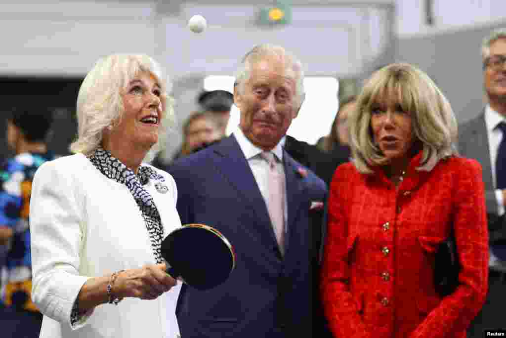 Britain&#39;s Queen Camilla plays table tennis next to Britain&#39;s King Charles, Brigitte Macron, wife of French President Emmanuel Macron as they meet local youth sports associations in Saint-Denis near Paris.