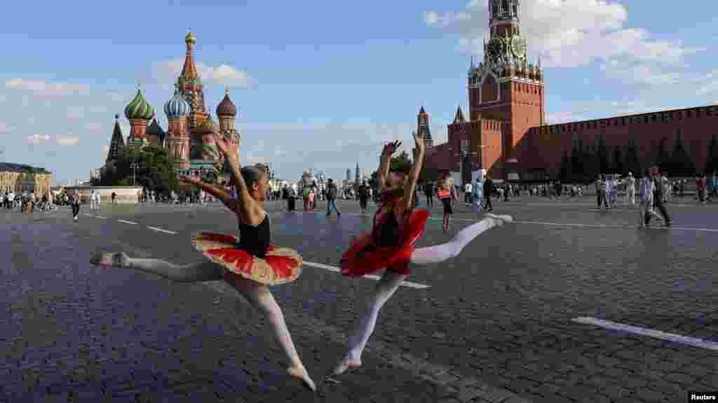 Dua anak perempuan memperagakan tari balet berpose di dekat Katedral St. Basil dan Menara Spasskaya Kremlin di Lapangan Merah di pusat kota Moskow, Rusia. (Reuters)