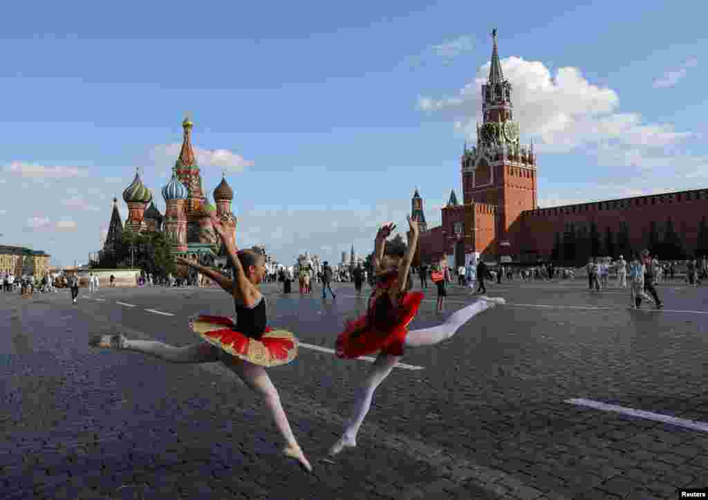 Girls in ballet dresses pose near St. Basil&#39;s Cathedral and the Kremlin&#39;s Spasskaya Tower in Red Square in central Moscow, Russia.