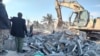 Members of Iraqi Shiite Popular Mobilization Forces clean the rubble after a US airstrike in al-Qaim, Iraq, Feb. 3, 2024. 