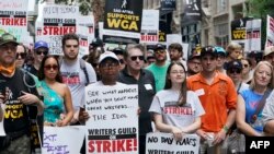 Members of the Writers Guild of America and the Screen Actors Guild pose for a photo while walking a picket line outside of Warner Bros. in New York on July 13, 2023.