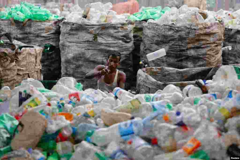 A worker removes labels from used plastic bottles in a plastic bottle recycling factory in Dhaka, Bangladesh.