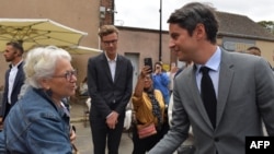 France's Prime Minister Gabriel Attal, right, shakes hands with a supporter during a campaign visit in Chatres, France, on July 2, 2024, ahead of the second round of France's legislative elections.