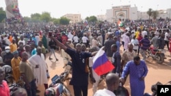 FILE - Nigeriens, some holding Russian flags, participate in a march called by supporters of coup leader Gen. Abdourahmane Tchiani in Niamey, Niger, on July 30, 2023.