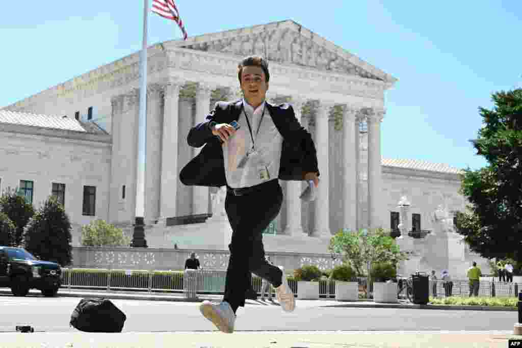 A journalist runs across the U.S. Supreme Court plaza carrying an opinion to a news correspondent as the court handed down decisions, in Washington. Former President Donald Trump hailed a &quot;big win&quot; for democracy after the Supreme Court ruled that presidents have presumptive immunity for official acts -- a decision set to delay his trial for conspiring to overturn his 2020 election loss. (Photo by Drew ANGERER / AFP)