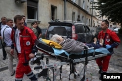Bolničari hitne pomoći iznose čoveka iz stambene zgrade pogođene u ruskom raketiranju, u Lavivu, Ukrajina, 6. jula 2023.