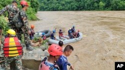 This handout photo from the Nepal Armed Police force, shows rescuers looking for the survivors after two buses were swept by a landslide off a highway and into a river about 120 kilometers west of the capital, Kathmandu, Nepal, July 12, 2024.