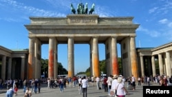 People walk in front of the Brandenburg Gate after Last Generation ("Letzte Generation") climate activists threw paint on the columns of the Brandenburg Gate in Berlin, Germany, Sept. 17, 2023. 