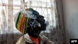 FILE - A man blows smoke after inhaling crystal meth in Glen View township, Harare, Zimbabwe on June 9, 2021.