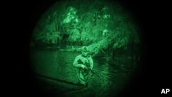 A Ukraine Special Operations Forces soldier walks through water on the shores of the Dnipro River using night vision goggles during a night mission in Kherson region, Ukraine, on June 11, 2023. (Felipe Dana/AP)