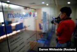 FILE - Seorang jurnalis tengah mengambil gambar loket tiket Malaysia Airlines di Jakarta 18 Juli 2014. (Darren Whiteside/REUTERS)