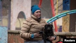 A local resident with her dog sits near her residential building damaged during a Russian missile strike in Kyiv, Ukraine.