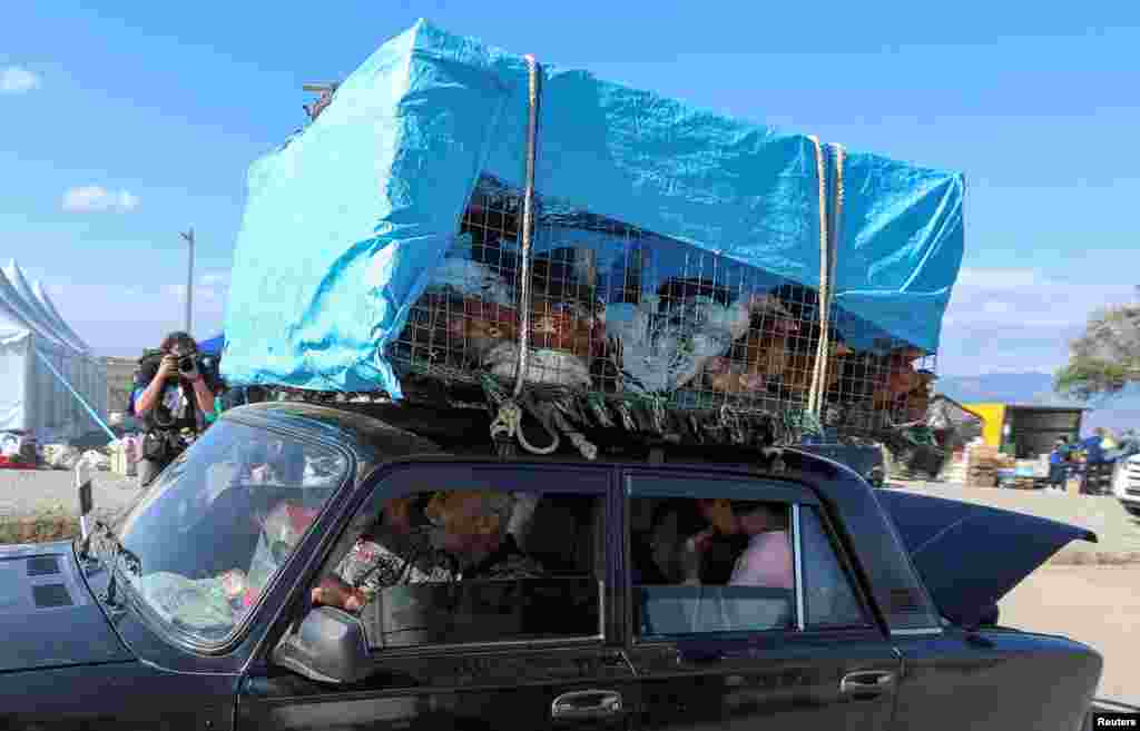 Refugees from Nagorno-Karabakh region ride in a car transporting chickens upon their arrival in the border village of Kornidzor, Armenia. REUTERS/Irakli Gedenidze&nbsp;